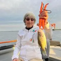 A woman holding up a fish on top of a boat.
