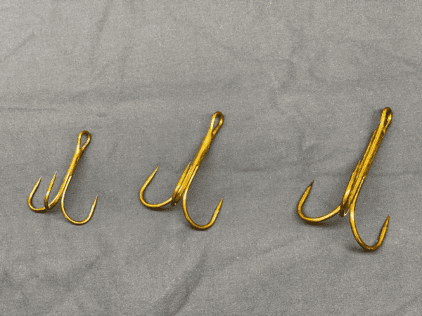 A group of three fish hooks on top of a sheet.