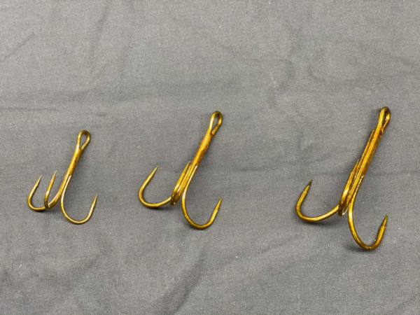 A group of three fish hooks on top of a sheet.