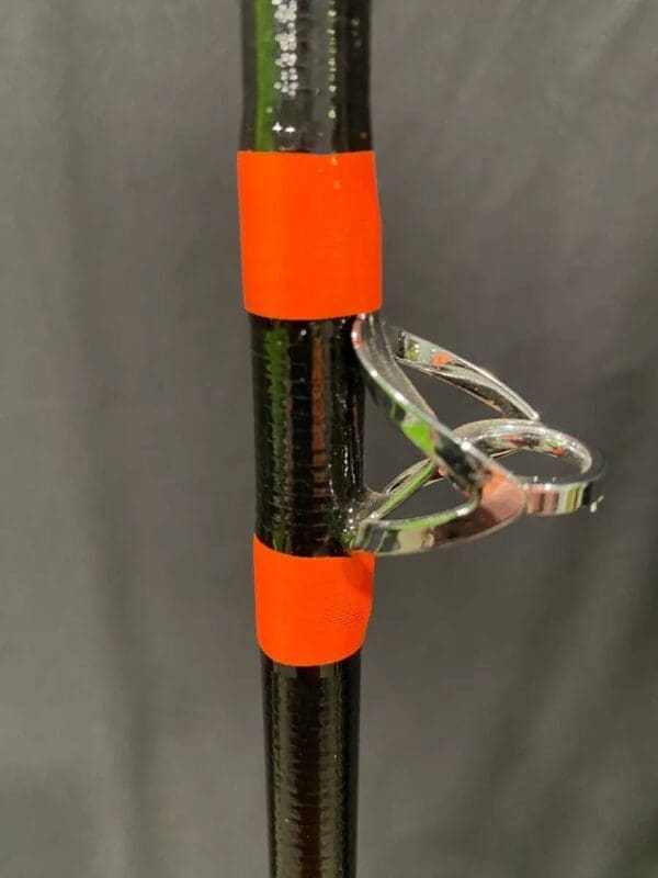 A black and orange pole with a pair of scissors on top.