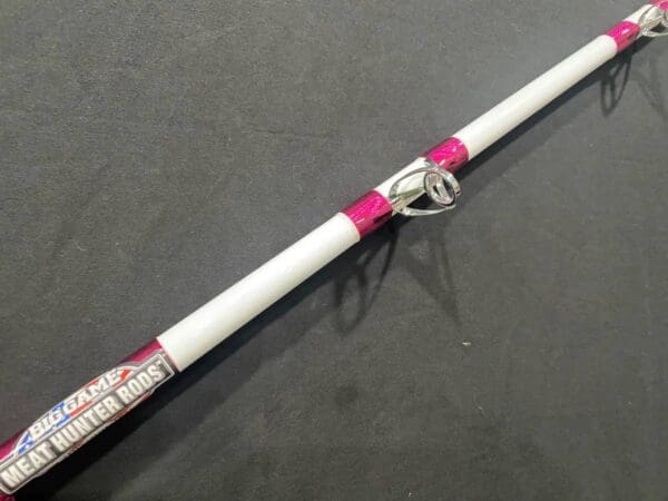 A white and pink fishing rod on top of a table.