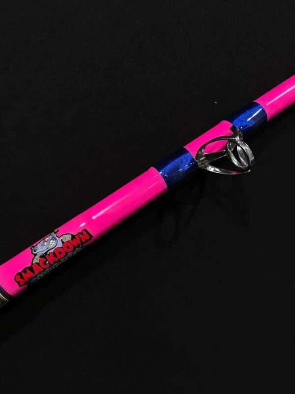 A pink fishing rod with blue and red handles.