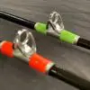 Two fishing rods with a green handle and orange handles.